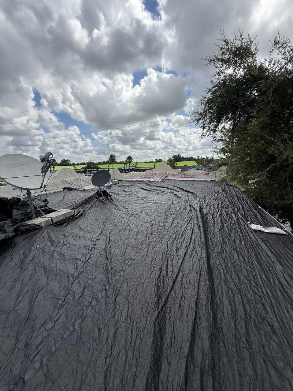 Section of hotel roof fully covered with heavy-duty tarp