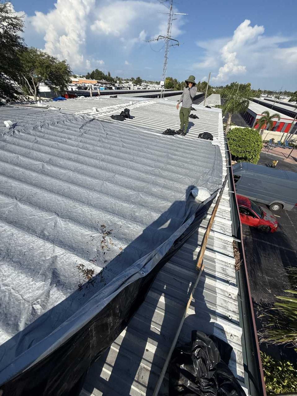 Restoration crew member walking a nearly fully tarped hotel roof