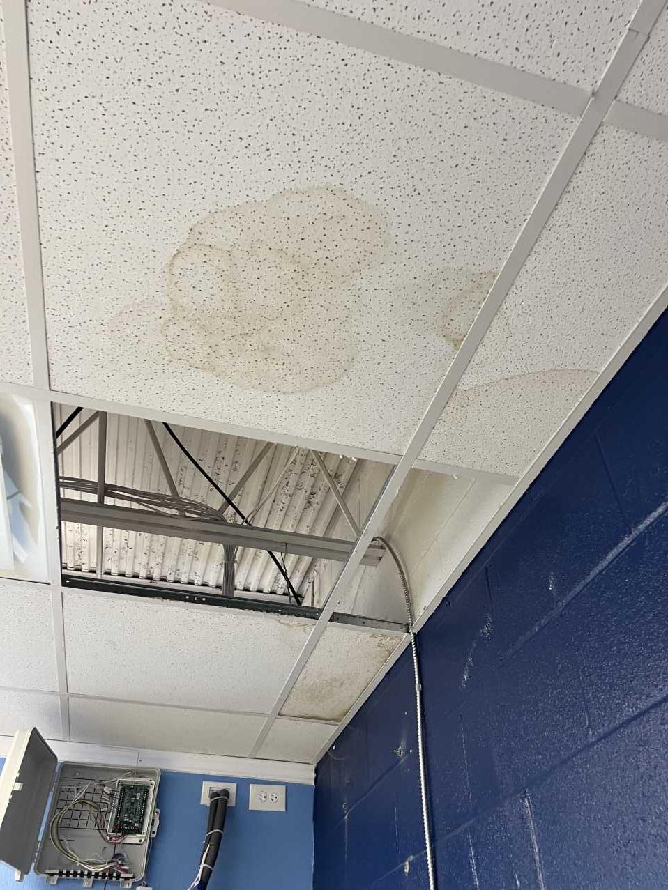 Close-up of storm-damaged ceiling tile and exposed roof decking in a commercial building