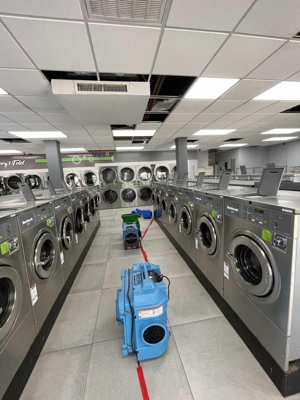 Air movers and dehumidifiers drying a commercial laundromat after water damage