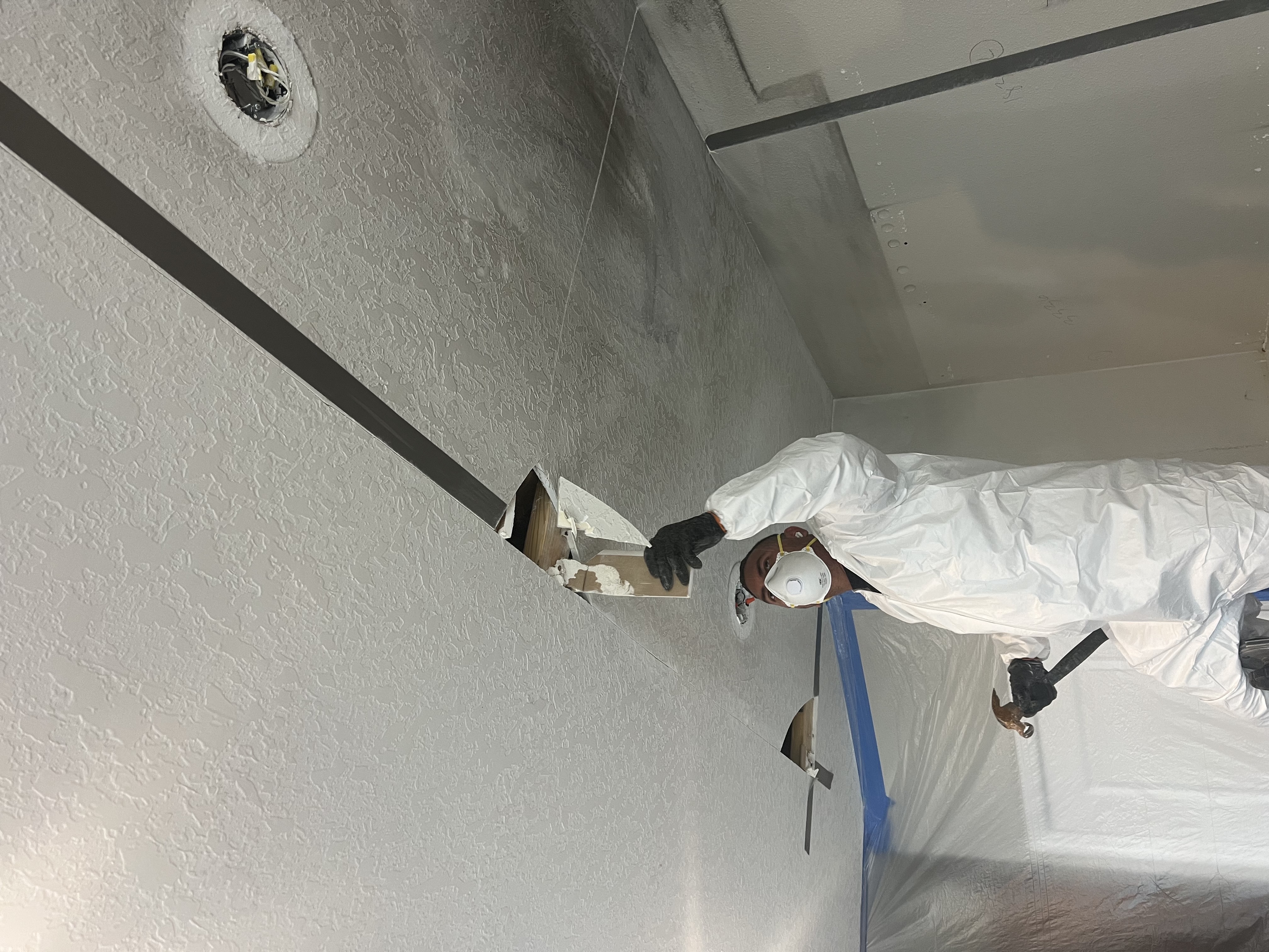 Restoration crew member removing a damaged section of ceiling after a fire