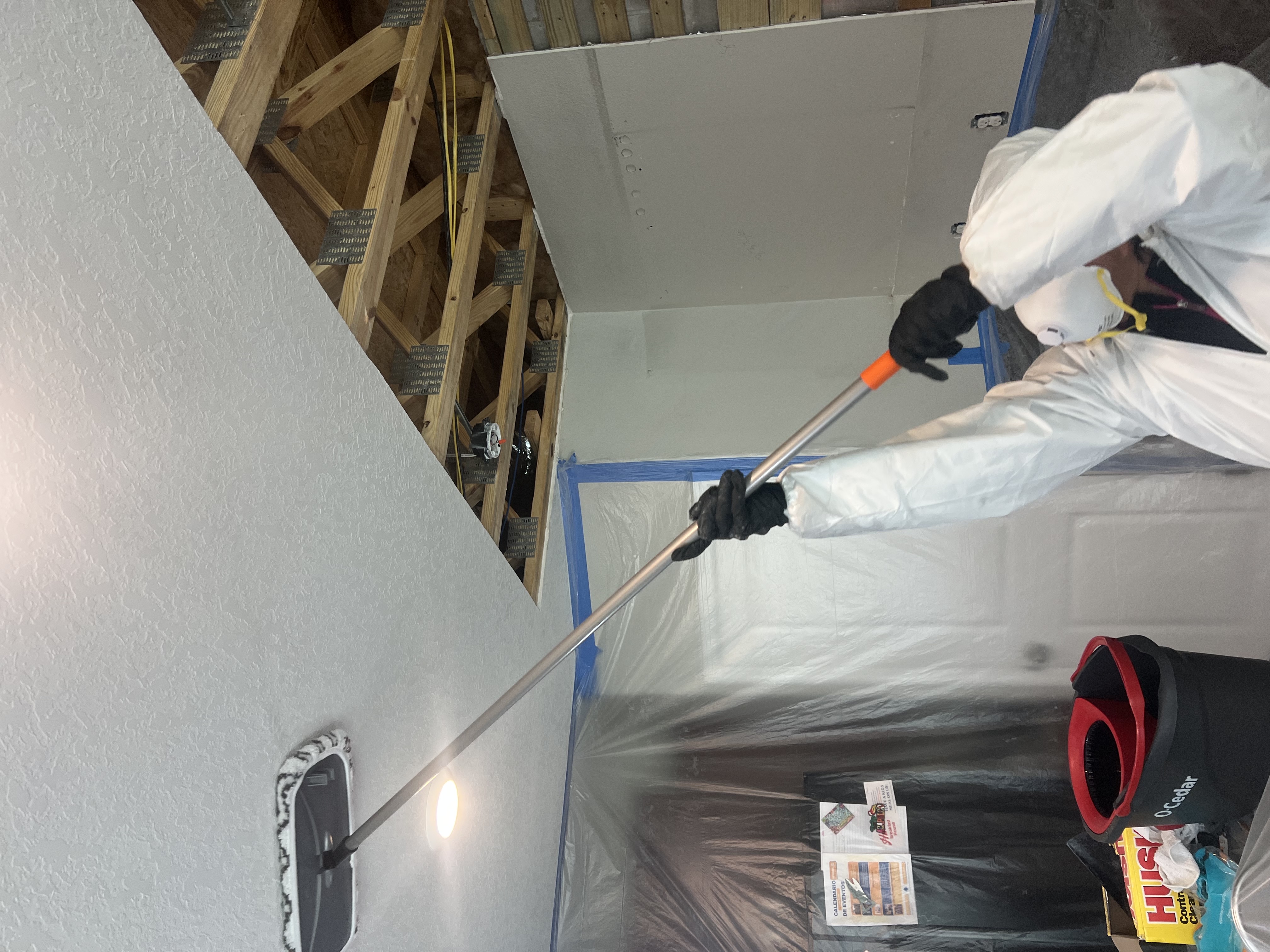 Restoration technician cleaning soot from a kitchen ceiling after a fire