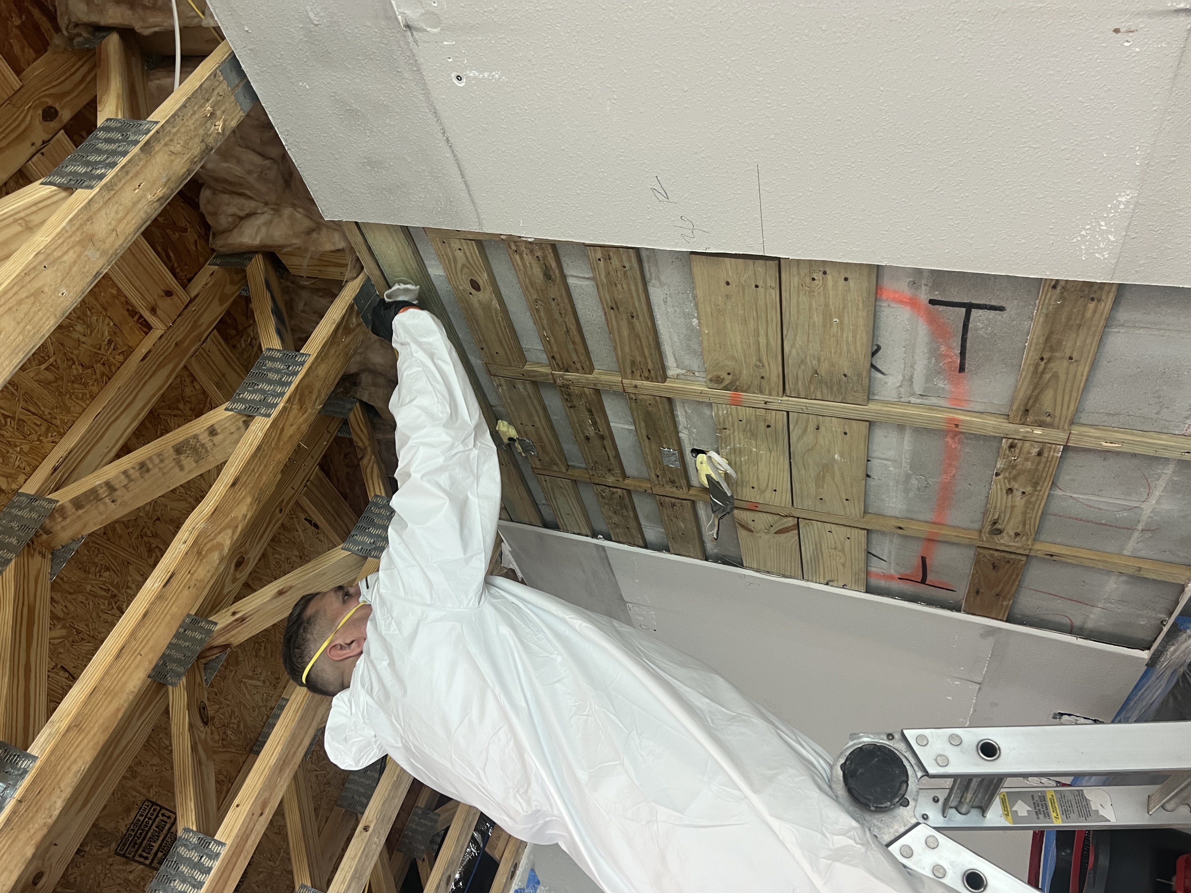 Restoration technician inspecting an open wall cavity after fire damage