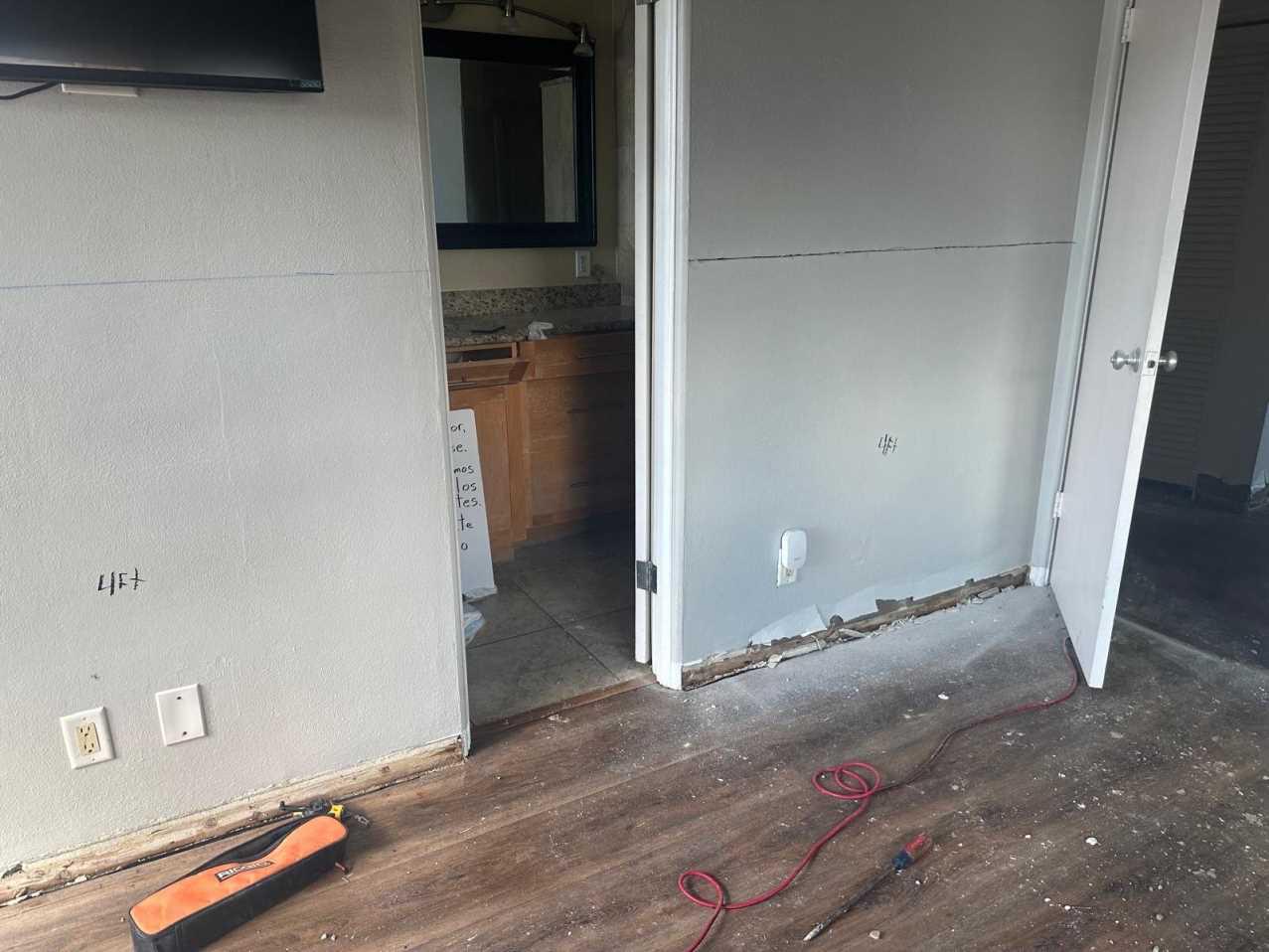 Restoration crew marking flood cut height on walls after hurricane flooding