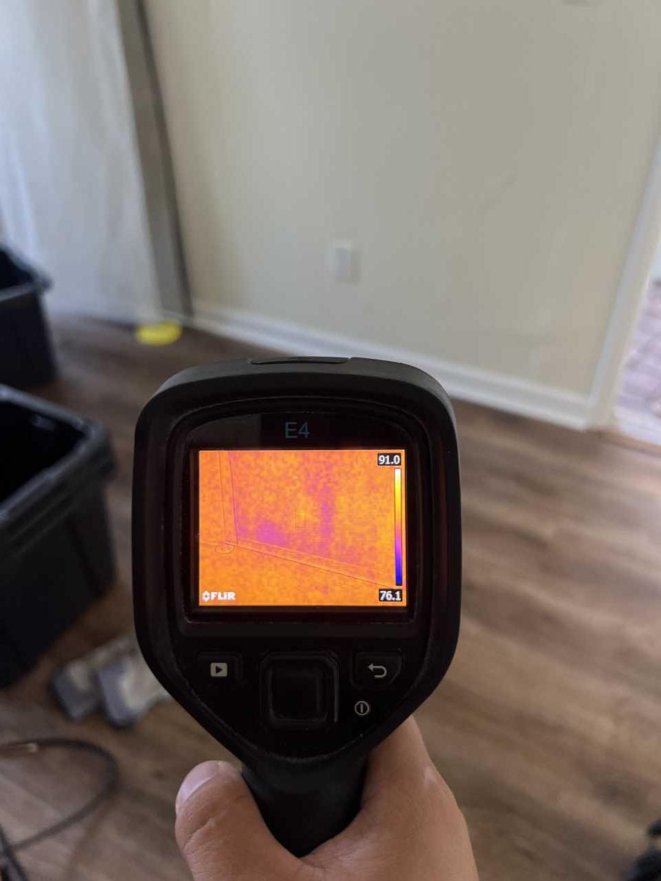 Restoration technician using a thermal imaging camera to detect moisture after hurricane flooding