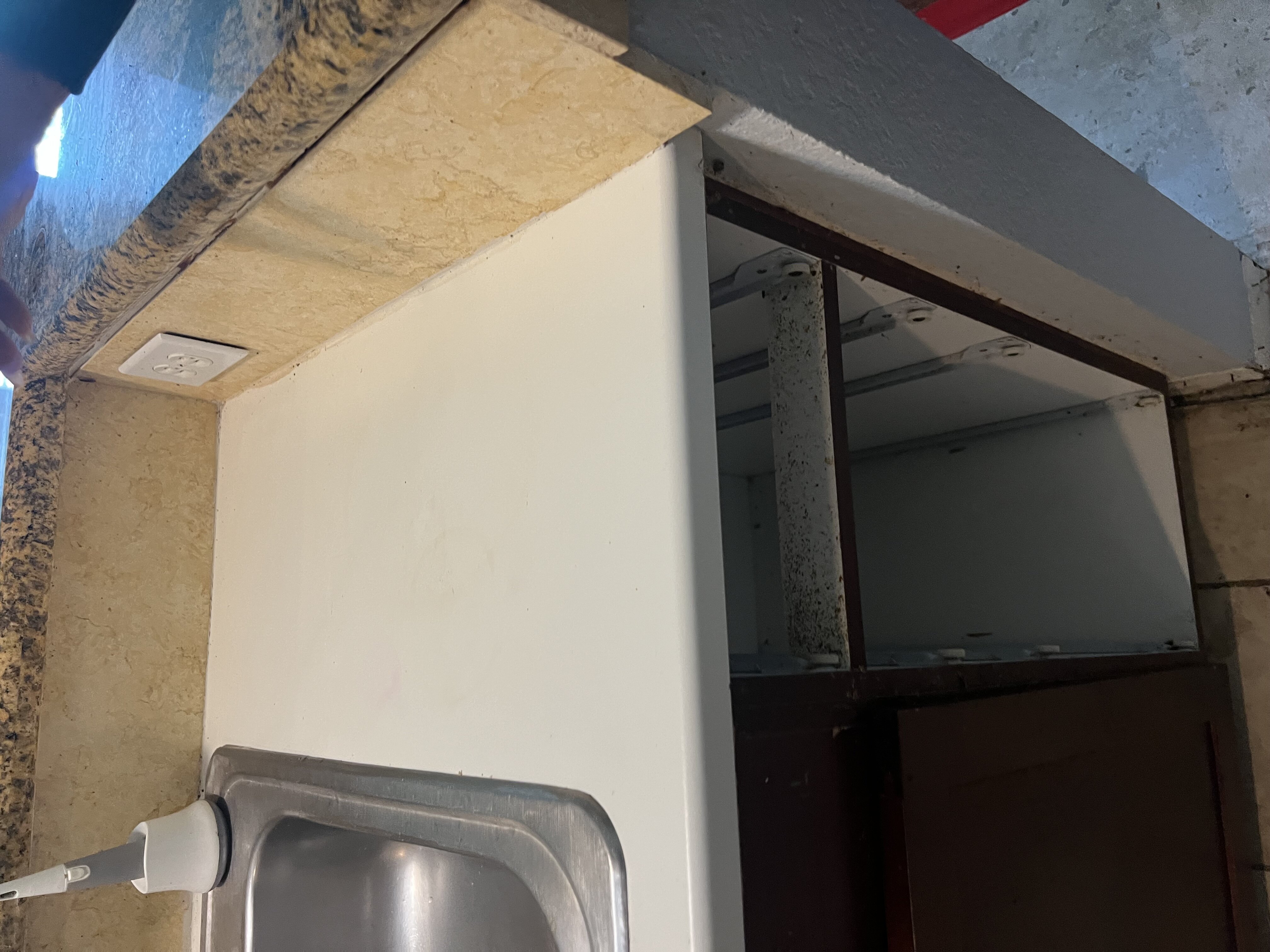 Restoration technician inspecting a kitchen cabinet for mold damage
