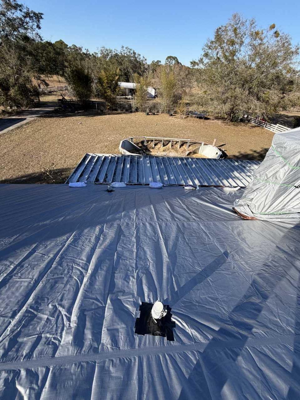 Roof tarp being deployed over a storm-damaged Florida roof