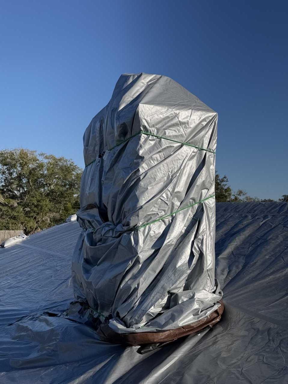 Roof vent wrapped and secured with tarp material during emergency roof tarping