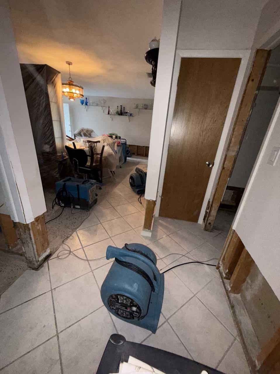 Hallway with flood cut drywall and an air mover running during storm restoration