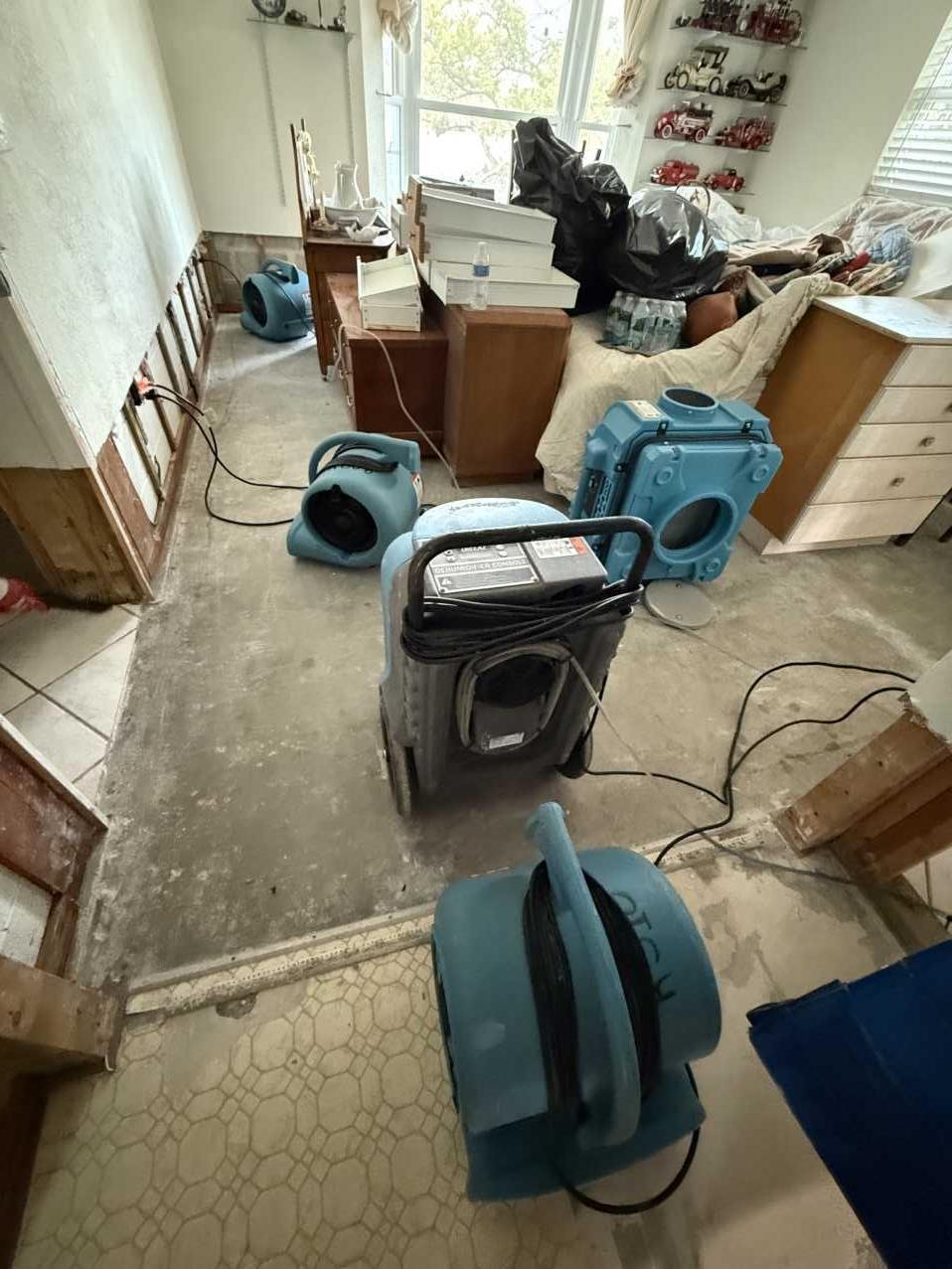 Florida home room stripped to the slab with air movers and dehumidifiers running after storm water intrusion