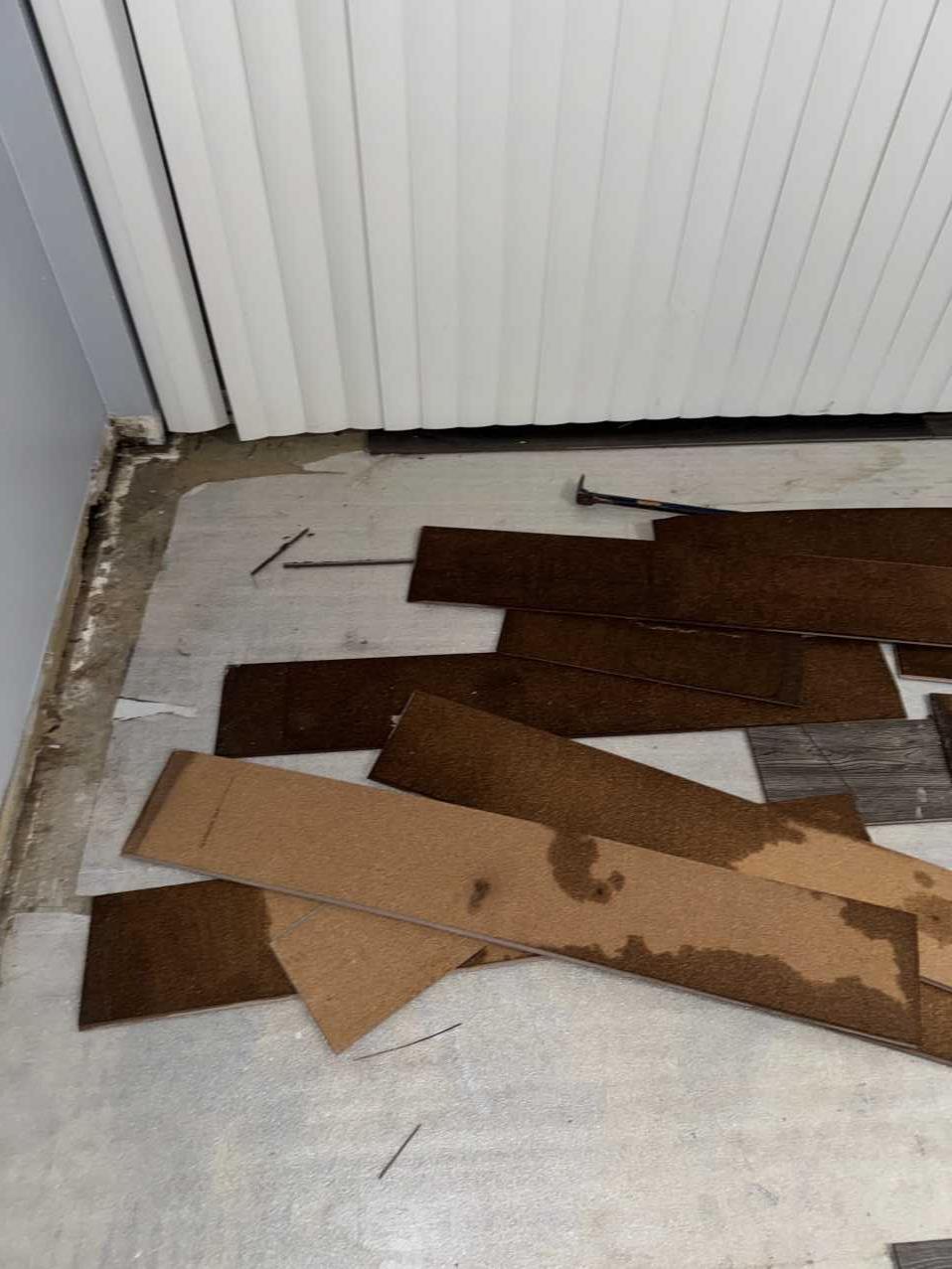 Pile of removed water-damaged vinyl flooring during restoration