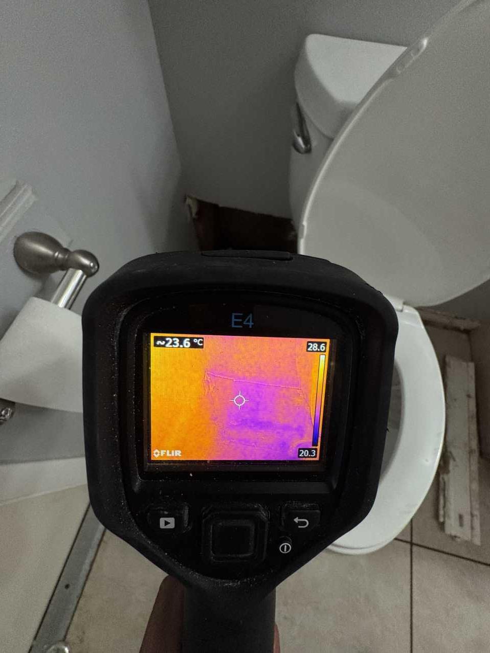 Restoration technician using a thermal imaging camera to detect hidden moisture after a pipe burst
